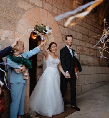 Des mariés qui sortent de la cérémonie dans un château avec des rubans